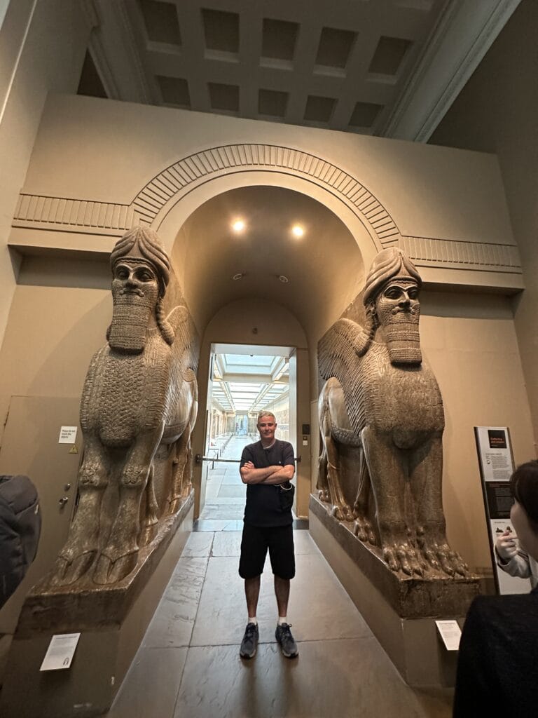 Turista brasileiro entre esculturas de lamassus assírios no British Museum em Londres.