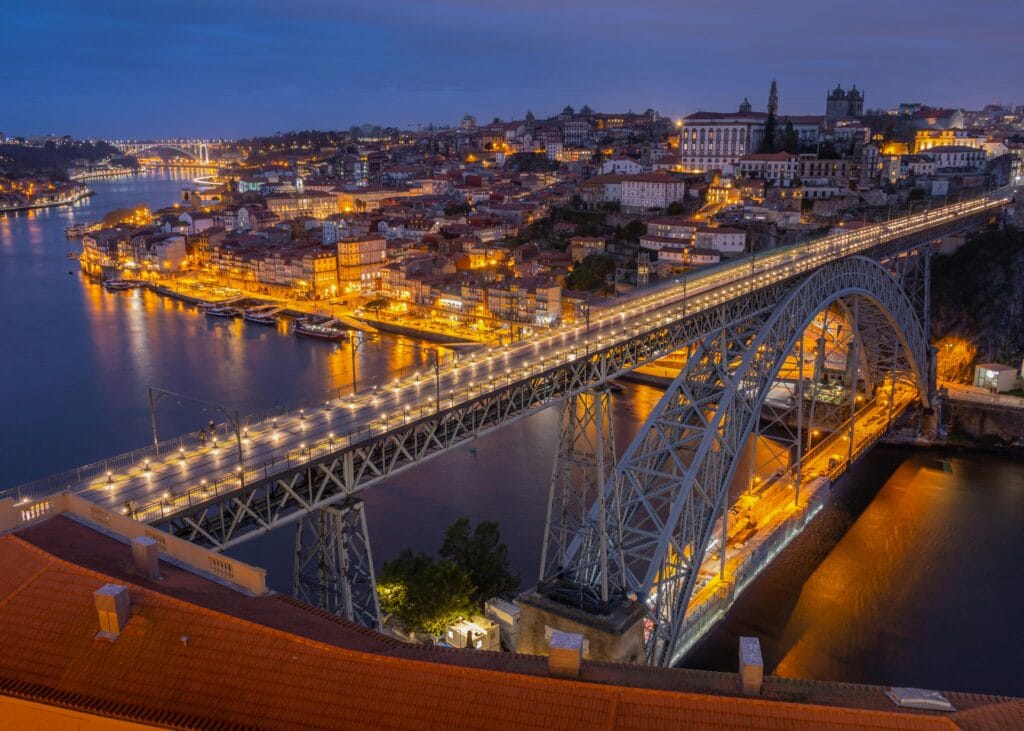Ponte Luís I iluminada à noite sobre o rio Douro na cidade do Porto, em Portugal. Viagem à Europa com orçamento limitado.