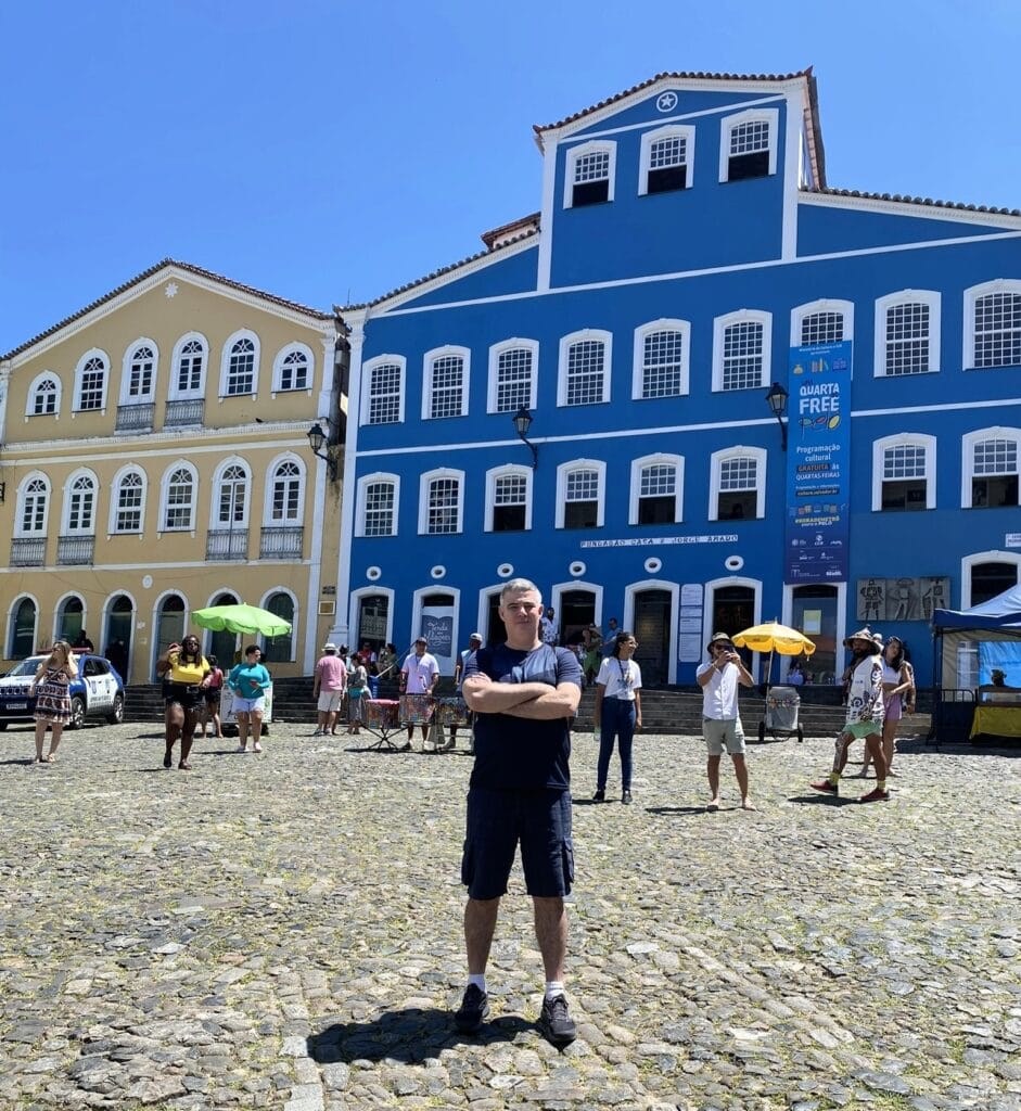 Turista posando em frente à Fundação Casa de Jorge Amado no Pelourinho, em Salvador, com casario colorido ao fundo. Roteiro de 5 dias em Salvador.