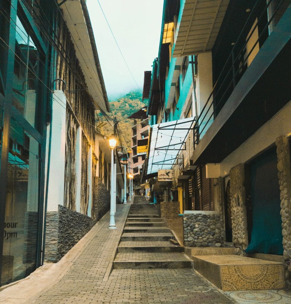 Escadaria entre prédios e comércios em rua estreita de Águas Calientes, Peru