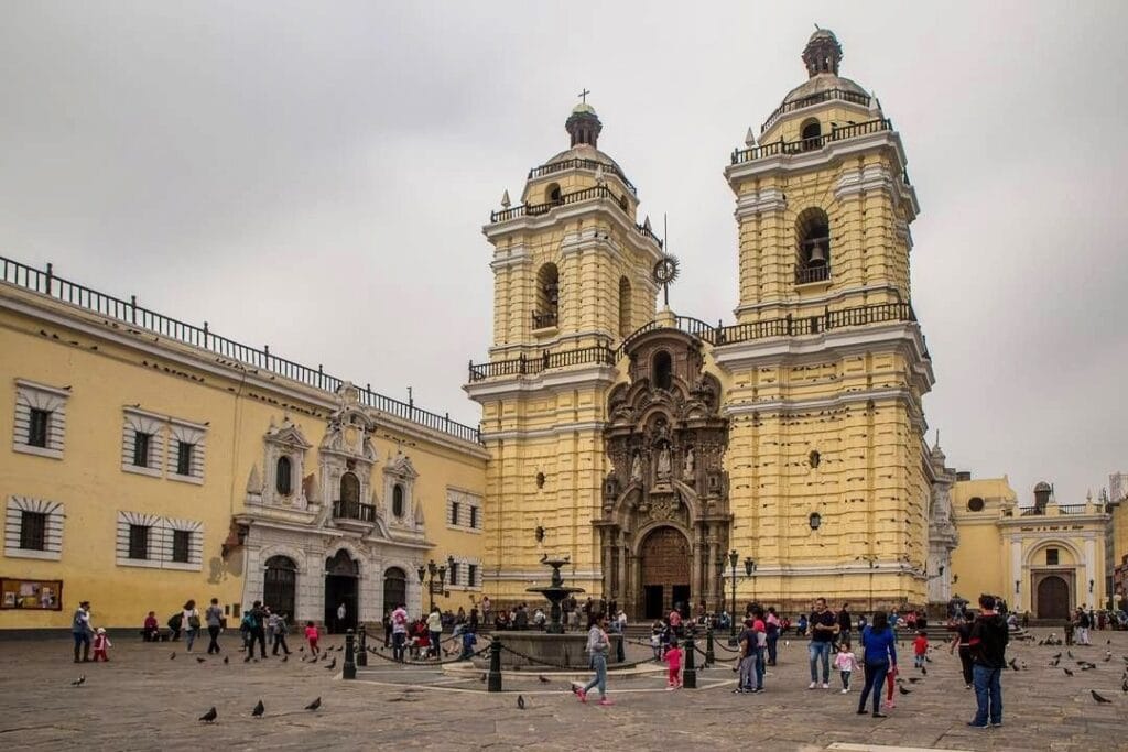 Fachada do Convento de San Francisco em Lima com visitantes na praça em frente. Lima e Cusco.