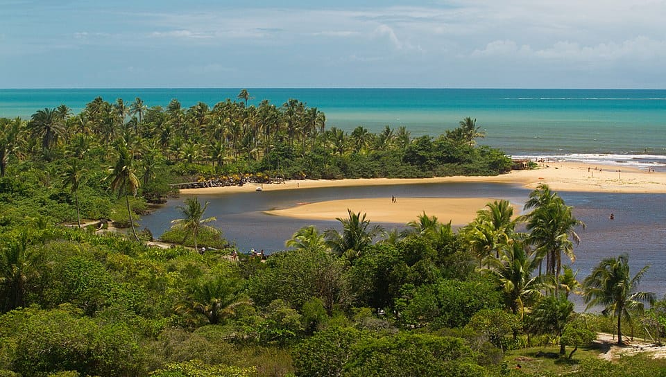 Vista aérea da Praia da Barra, em Caraíva, Bahia, onde o rio Caraíva encontra o mar, formando uma paisagem paradisíaca. Um dos destinos tendência mais bonitos do Brasil!