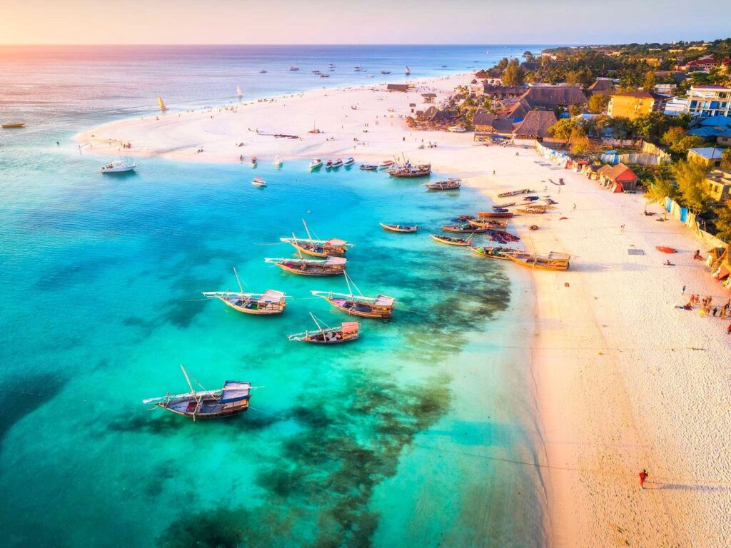 Vista aérea da praia de Nungwi em Zanzibar com barcos tradicionais sobre o mar turquesa.