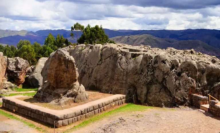 Rochas esculpidas no centro cerimonial de Q’enqo, com montanhas ao fundo