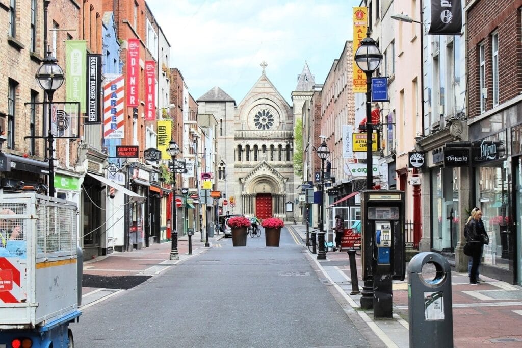 Rua Grafton no centro de Dublin, com prédios históricos e lojas.