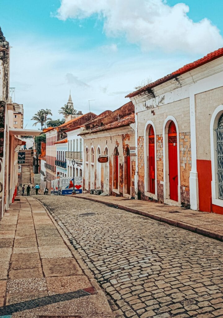 Rua de paralelepípedos com casarões coloridos e janelas vermelhas no centro histórico de São Luís, Maranhão