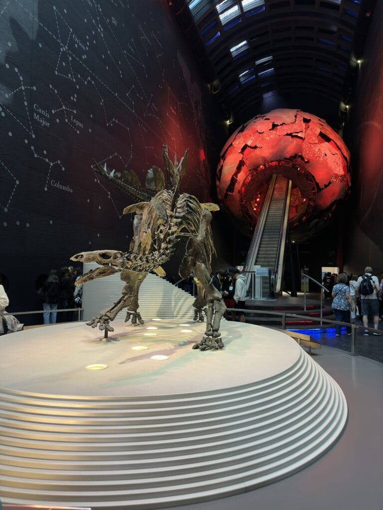 Escultura de dinossauro e esfera terrestre na entrada da galeria de ciências da Terra no Museu de História Natural, em Londres