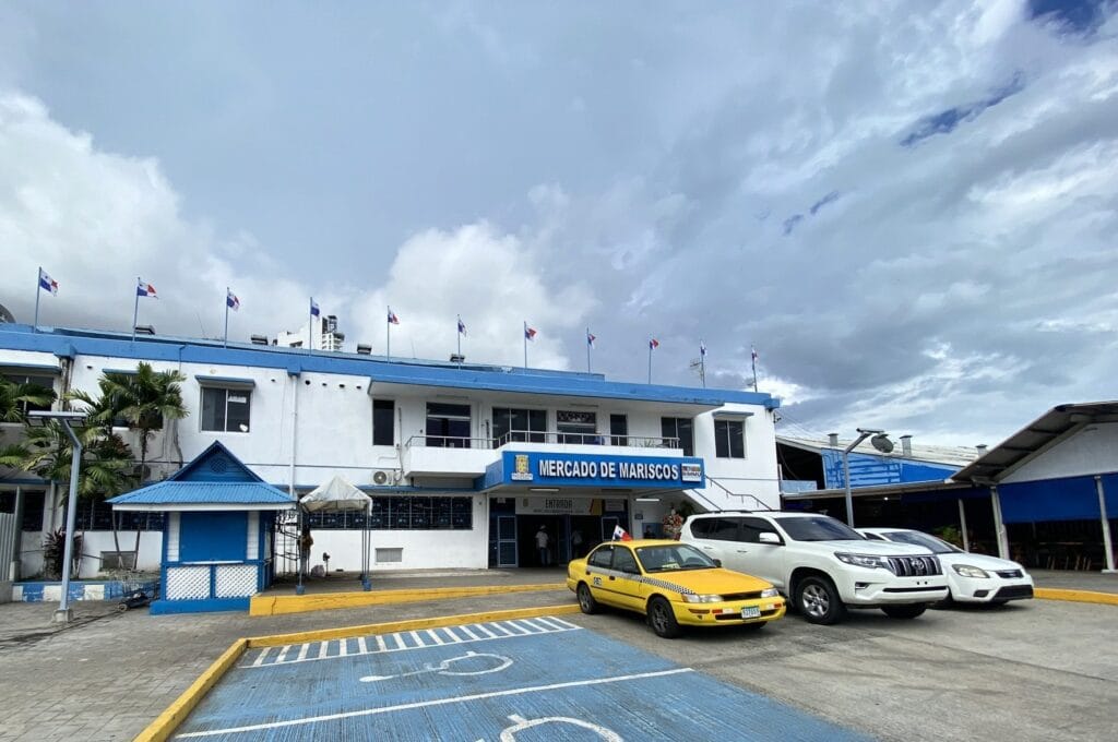 Fachada do Mercado de Mariscos na Cidade do Panamá com táxis e carros estacionados em frente