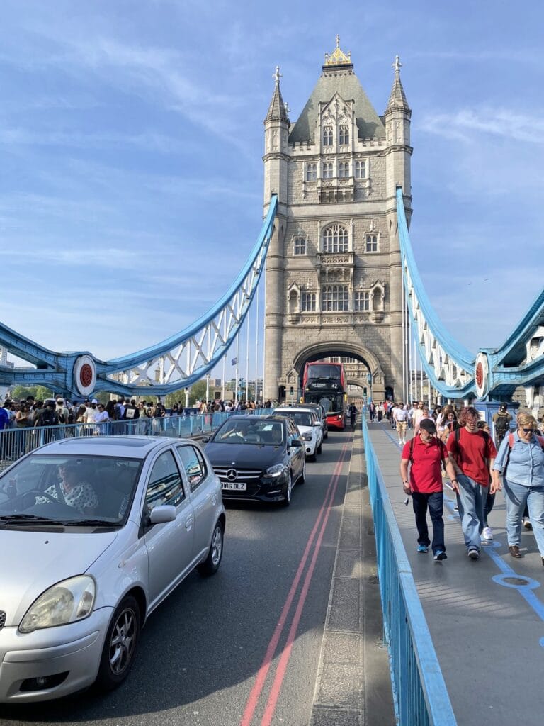 Vista frontal da Tower Bridge com carros e pedestres atravessando a ponte em Londres