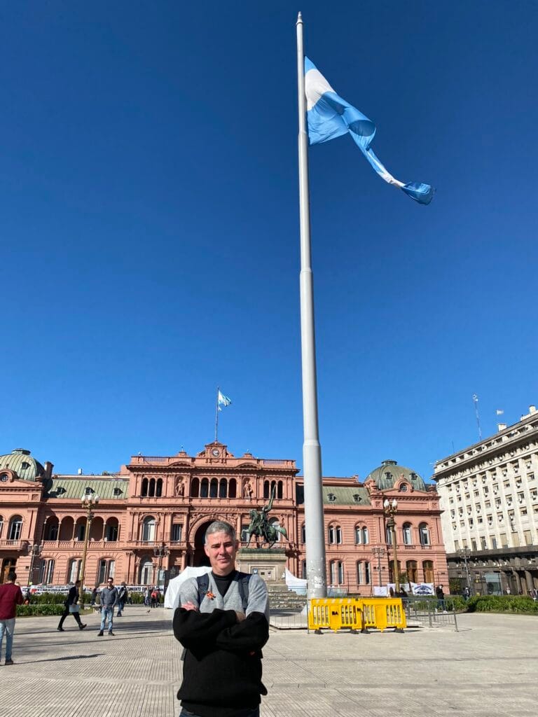 Turista posando em frente à Casa Rosada com a bandeira da Argentina ao fundo, em Buenos Aires. Roteiro de 6 Dias em Buenos Aires