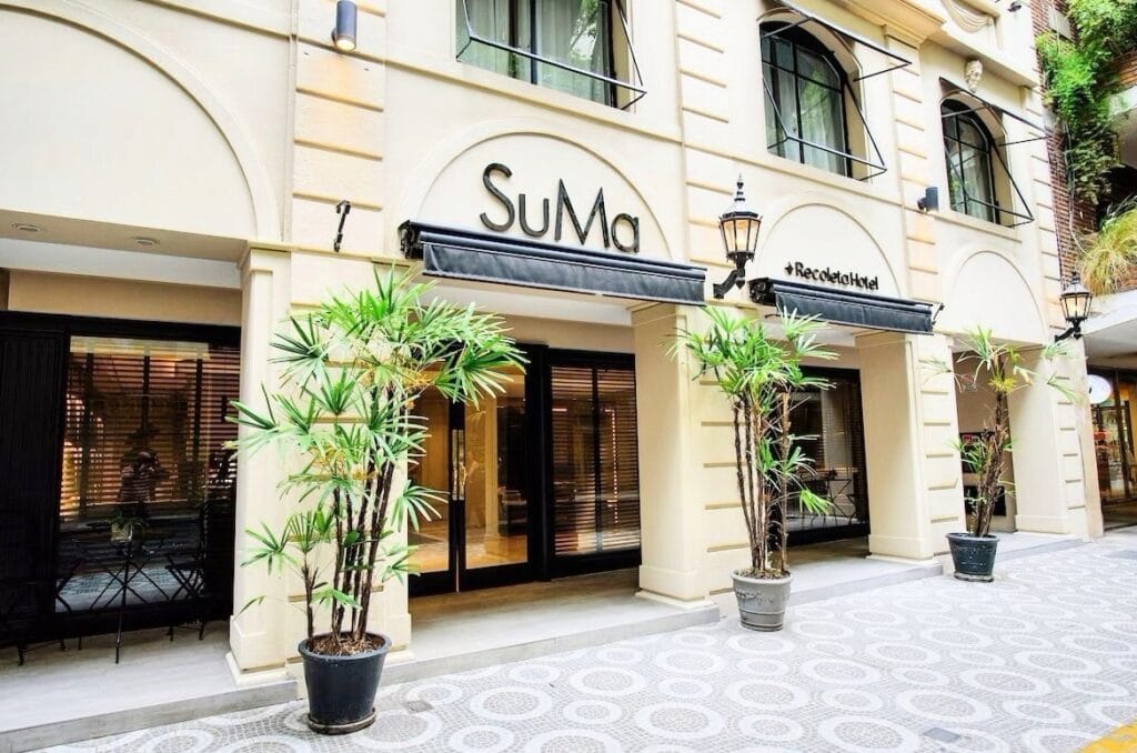 Fachada elegante do Hotel SuMa Recoleta em Buenos Aires, com vasos de plantas, janelas com grades pretas e toldos escuros sobre as entradas. Roteiro de 6 dias em Buenos Aires.